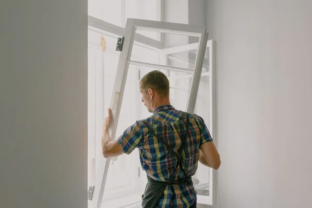 Ein Handwerker setzt ein Fenster in eine Wandöffnung ein — © Bild: Ksenia Chernaya auf Pexels.com